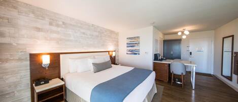 A hotel room with a large bed, bedside tables, a desk, and a chair.