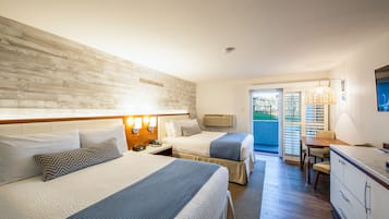 Een hotelkamer met twee bedden, een bureau en uitzicht op buiten.