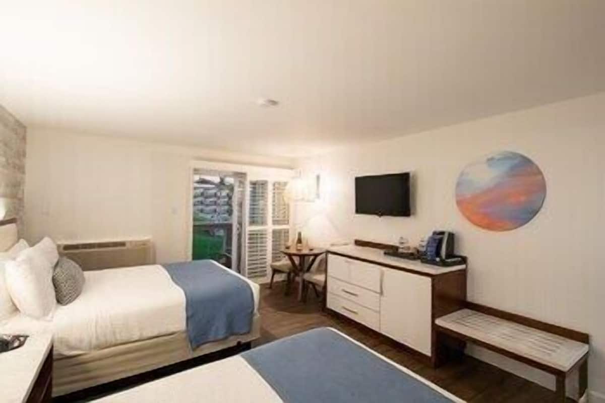 Habitación de hotel con cama, escritorio, silla, televisor y un cuadro en la pared.