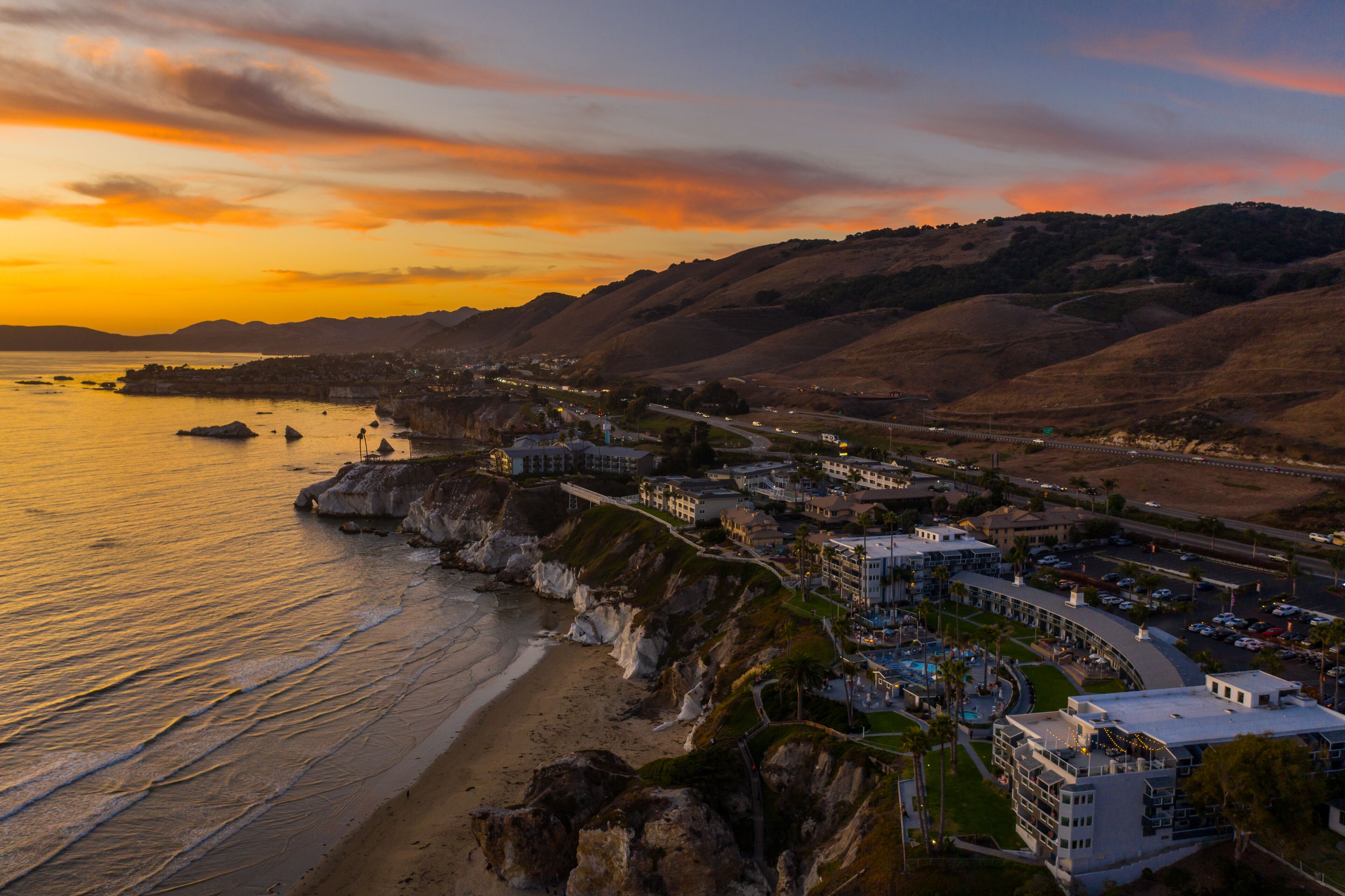 A coastal town with a beach, a marina, and a hotel with multiple buildings and a swimming pool.