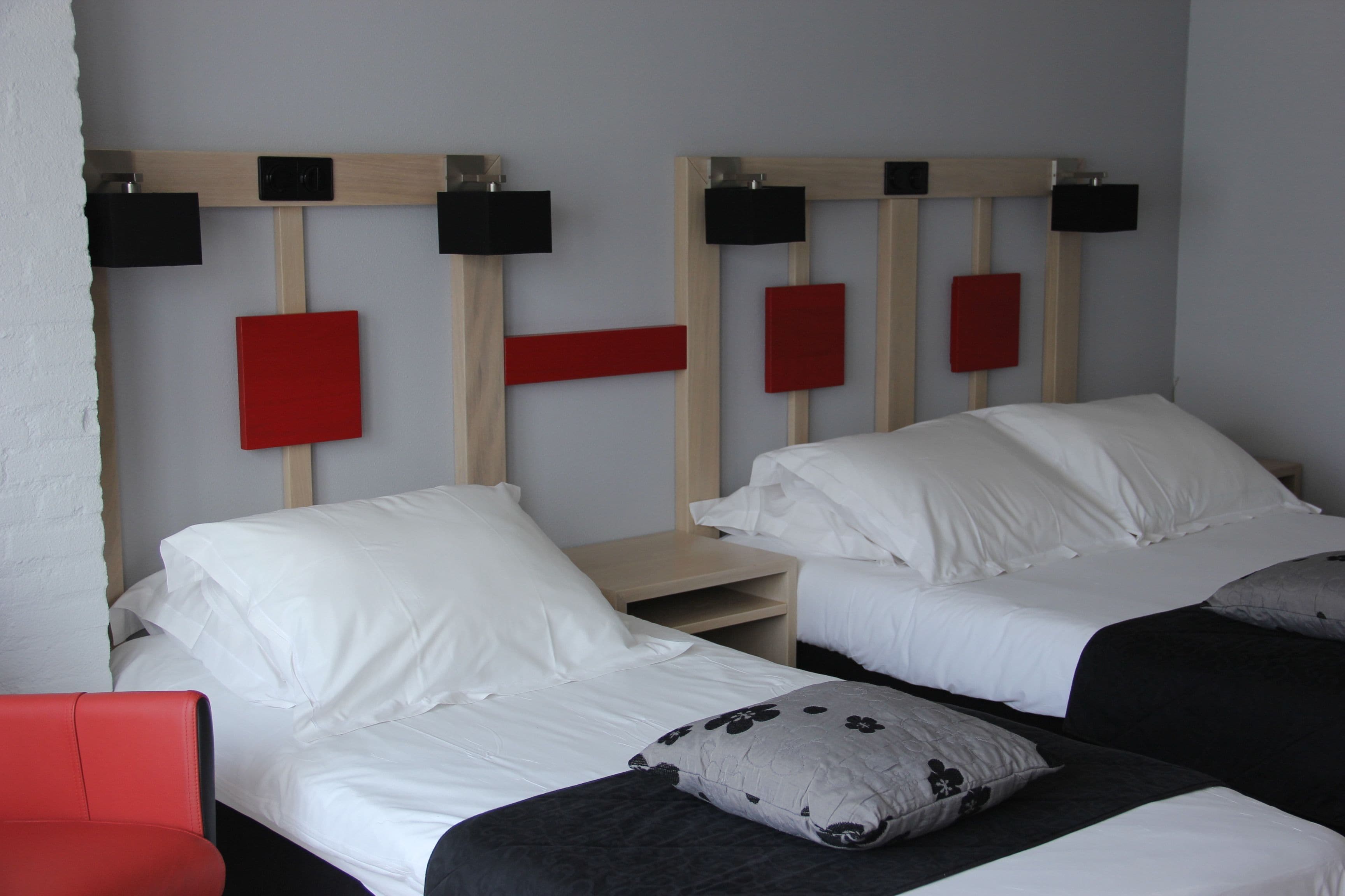 Een hotelkamer met twee bedden, elk voorzien van witte beddengoed en hoofdborden in zwart en rood.
