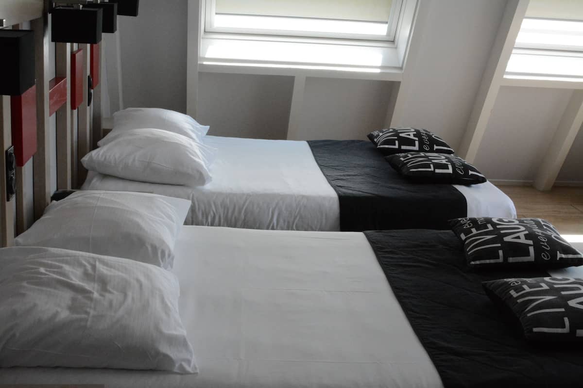 A hotel room with two beds, each with white and black bedding.