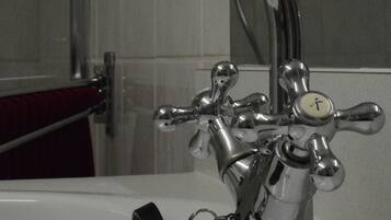 Un baño con grifo cromado, un mando visible y un llavero sujeto al grifo.