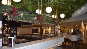 A bar area with a Christmas tree, hanging lights, and a marble counter.