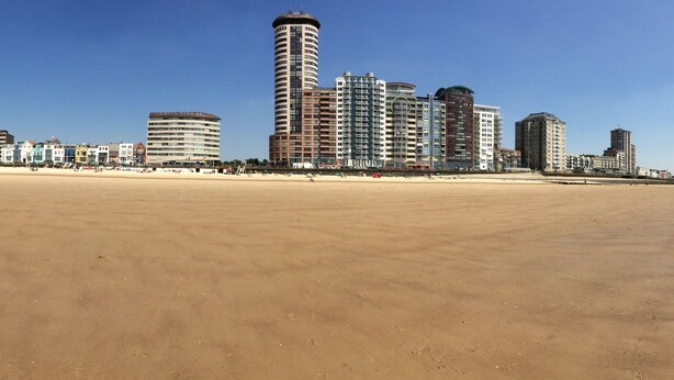 A wide sandy beach with a cityscape in the background.