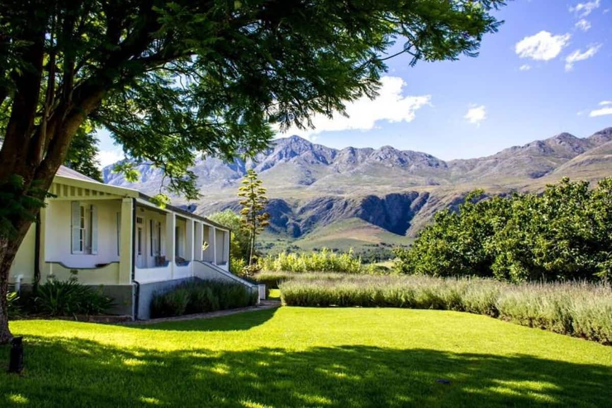 Une maison avec un porche à l’avant, une pelouse bien entretenue et une vue sur les montagnes en toile de fond.