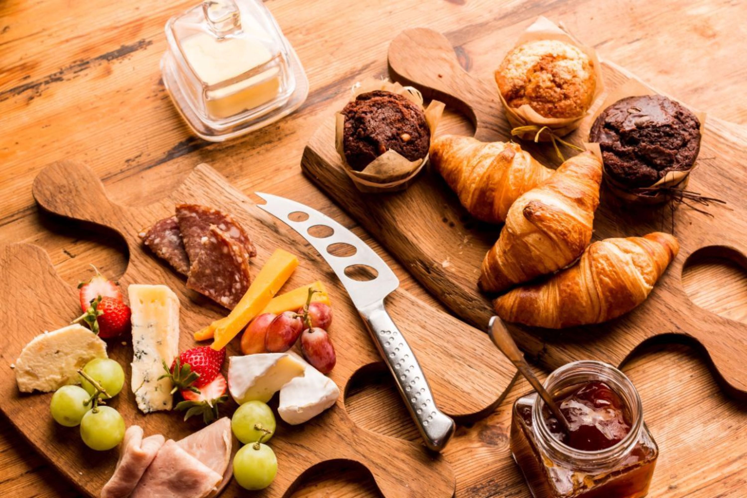 Une planche en bois sur laquelle sont disposés différents fromages, des raisins et un couteau.