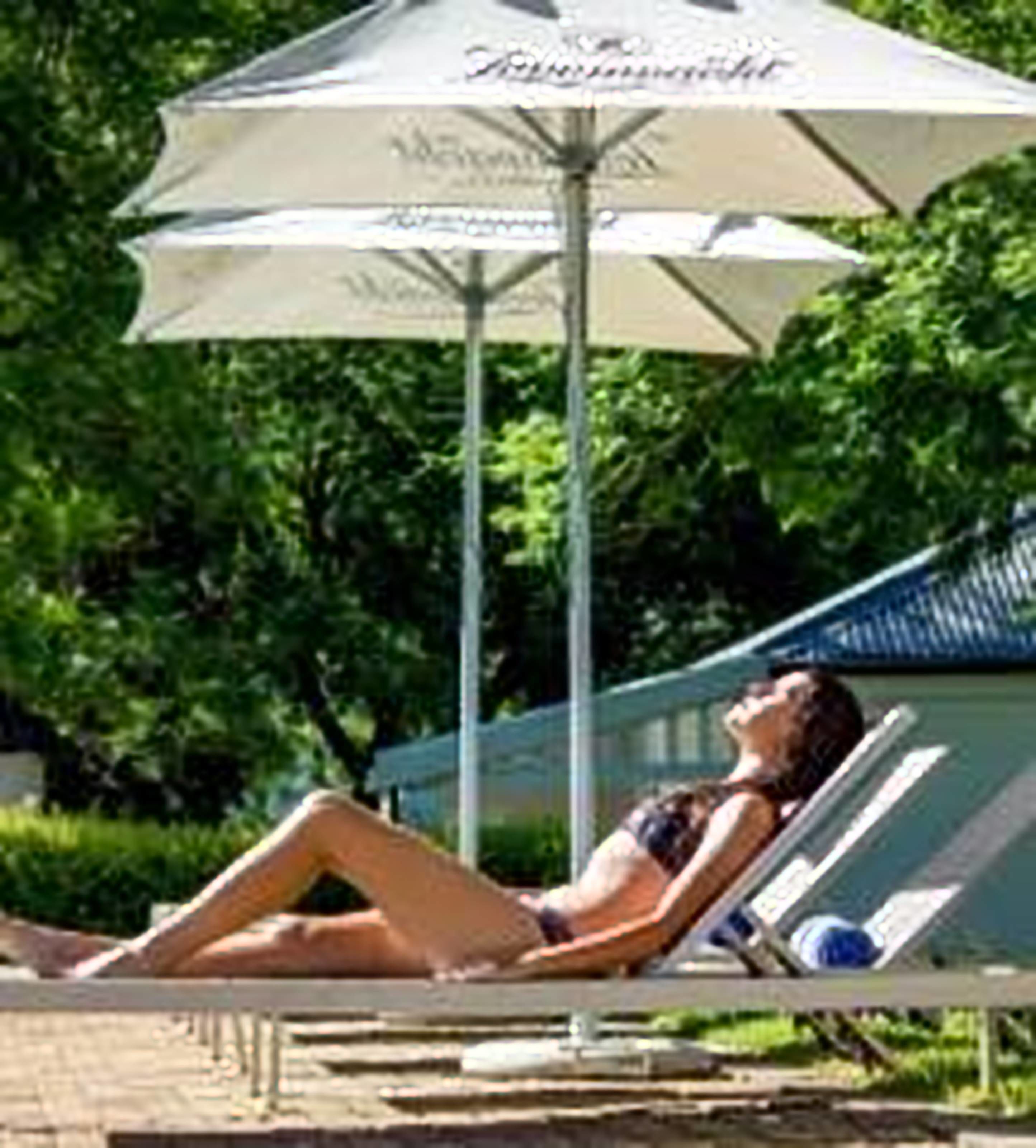 A person lying on a lounge chair under a canopy umbrella.