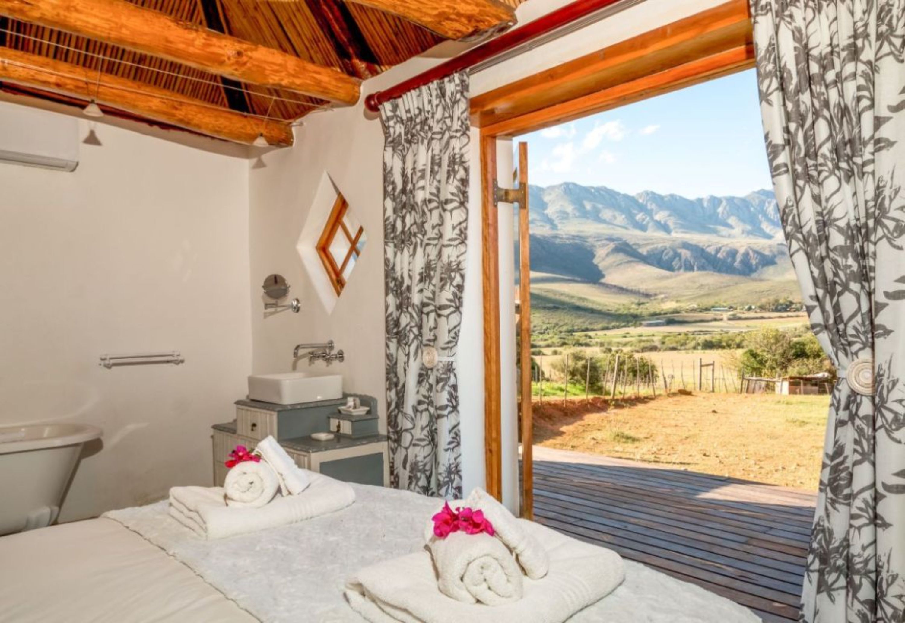 A bedroom with two beds, a bathroom, and a view of mountains.