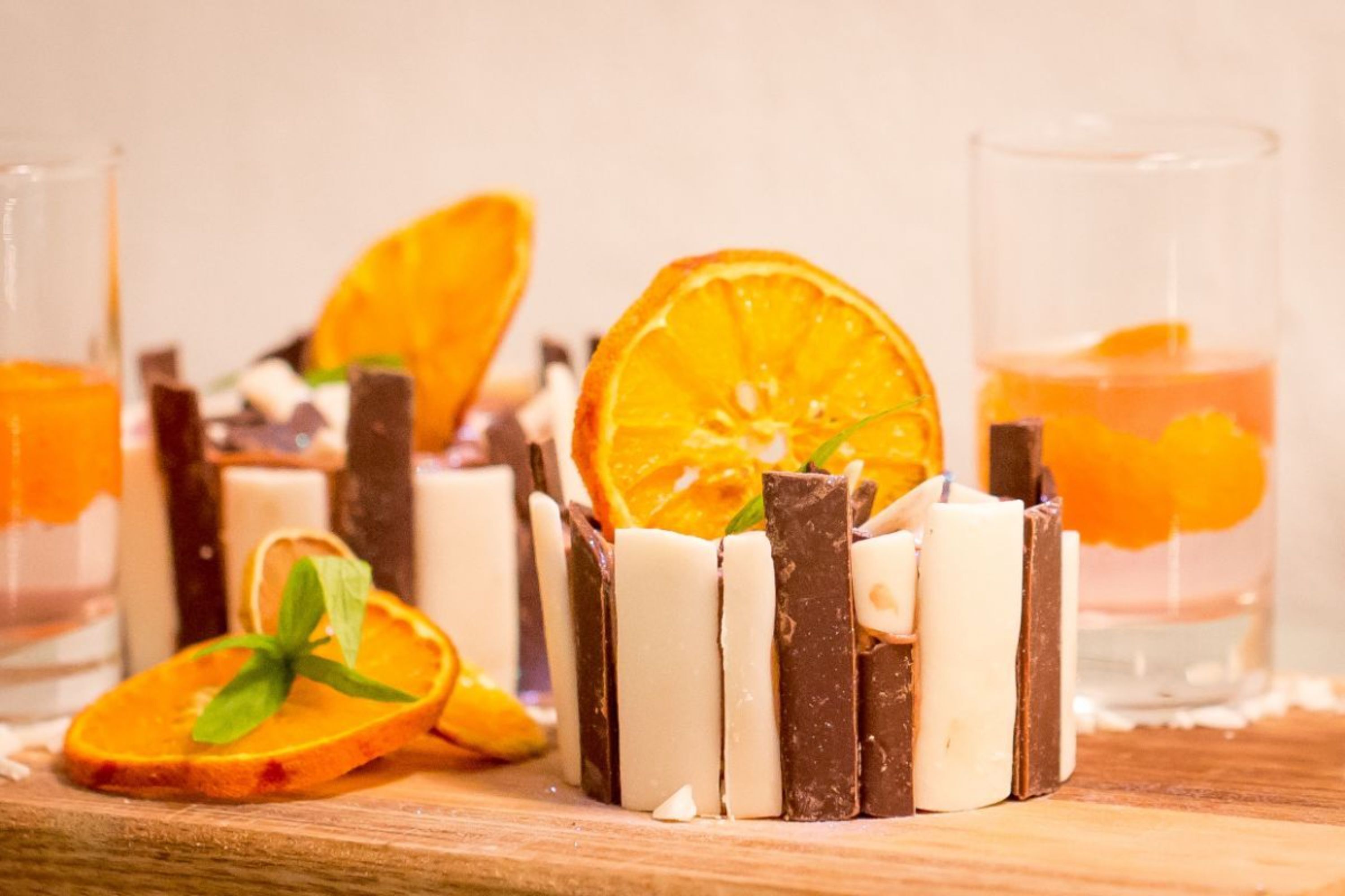A dessert with chocolate and white chocolate bars, orange slices, and mint leaves.