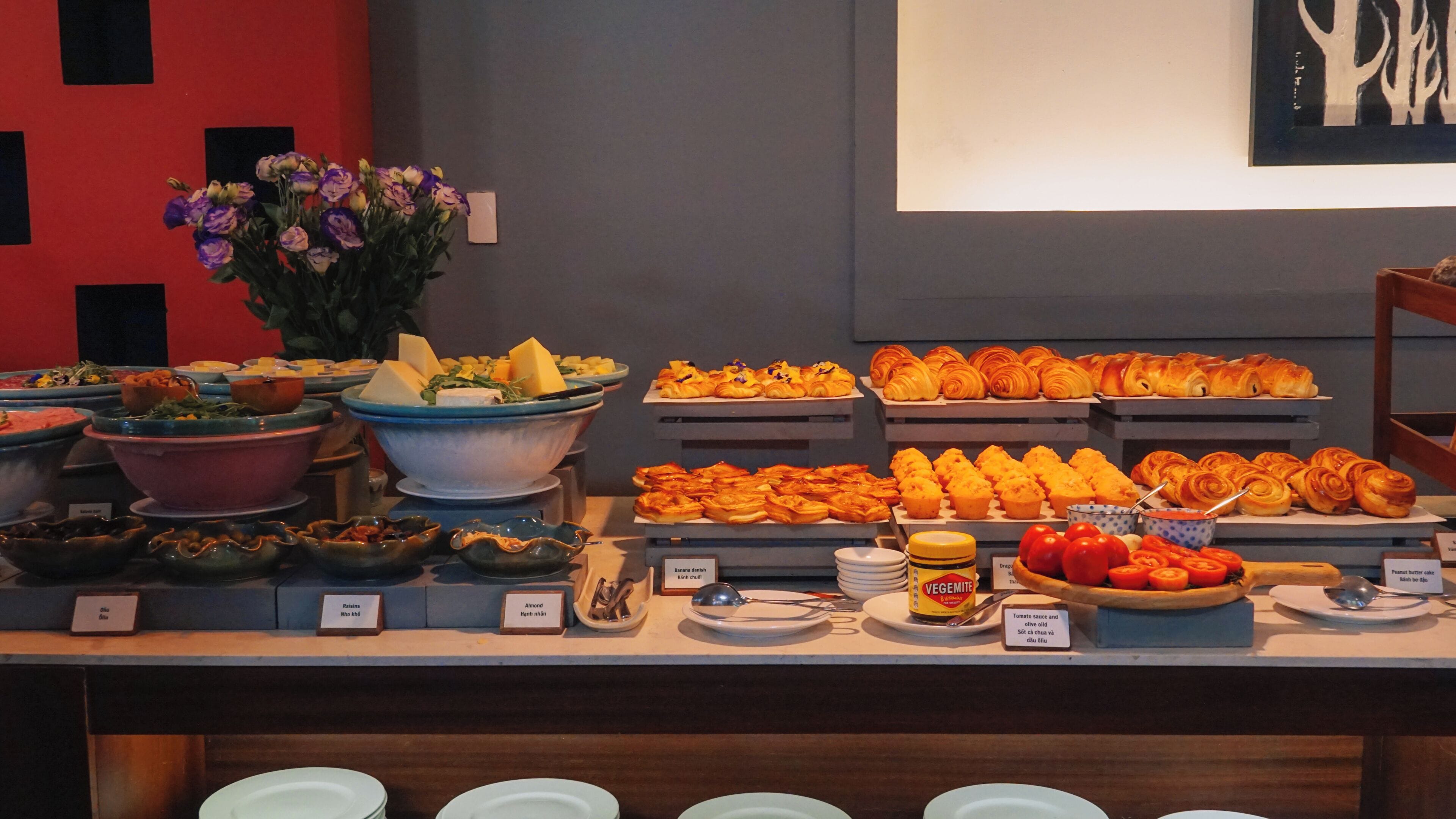 A buffet with various food items and a vase of flowers.