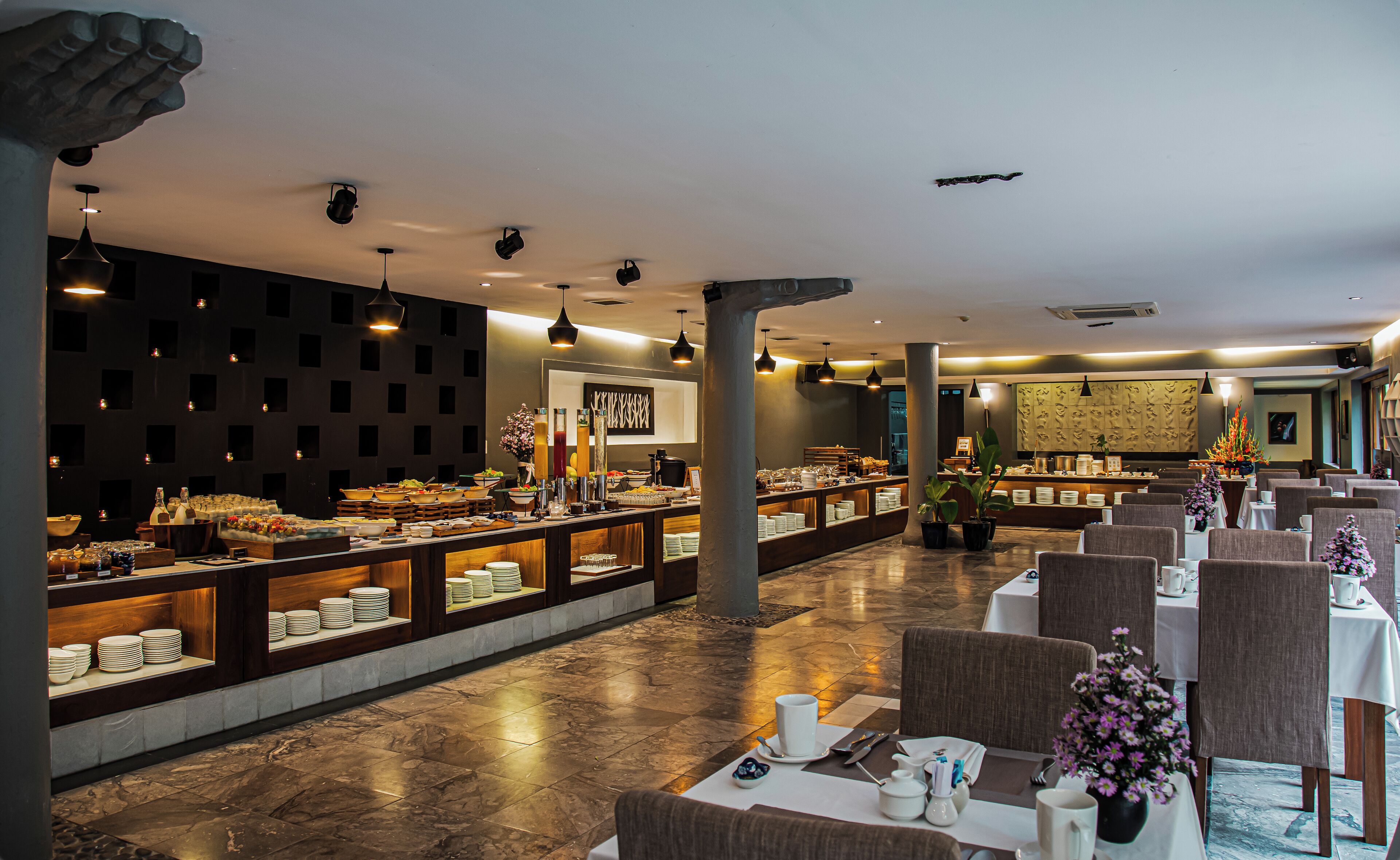 Un amplio vestíbulo de hotel con zona de buffet, asientos y un diseño de interiores moderno.