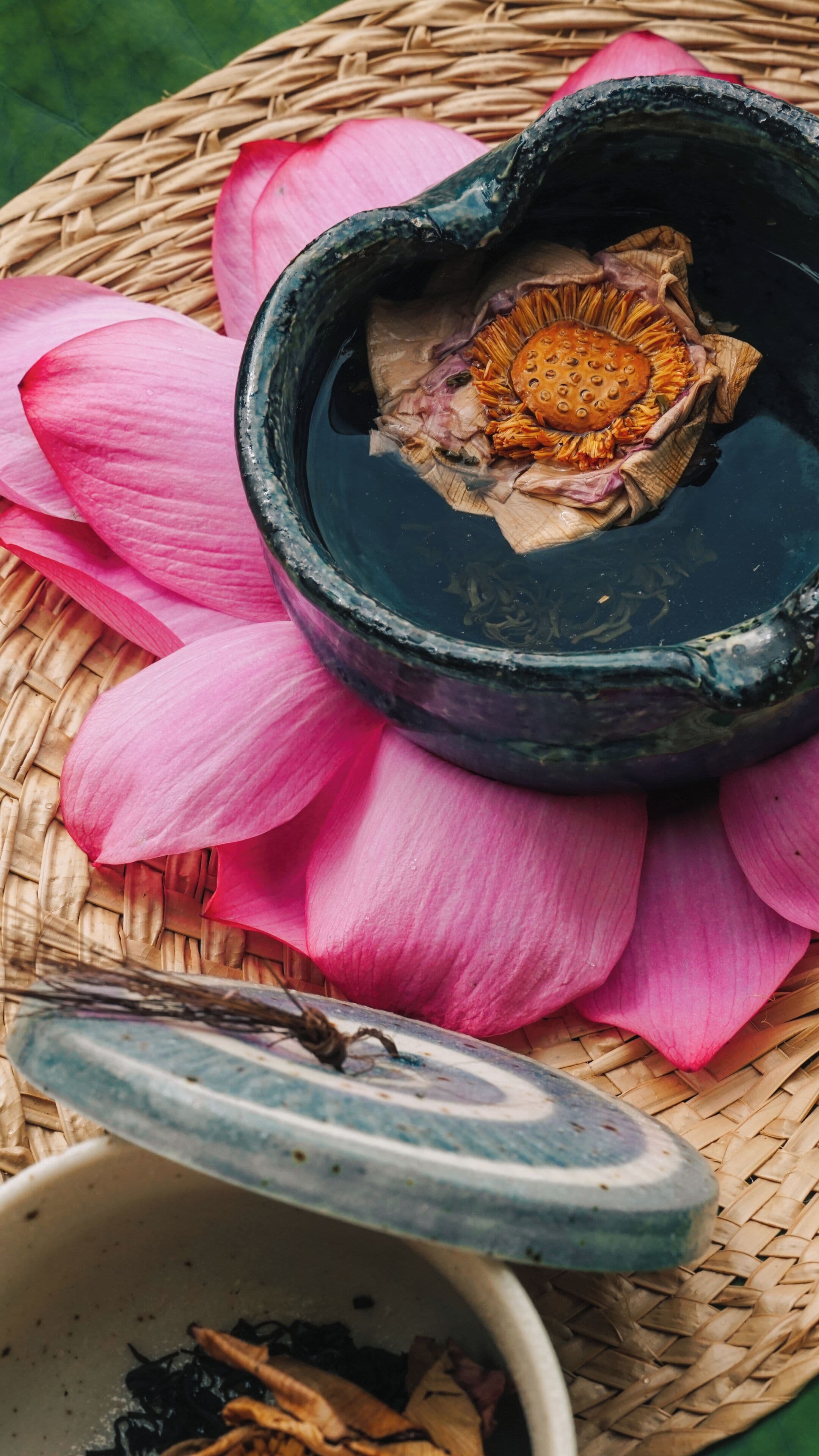 Ein traditionelles Teeservice mit Teekanne und Tasse, platziert auf einer gewebten Matte mit einer Lotusblume.