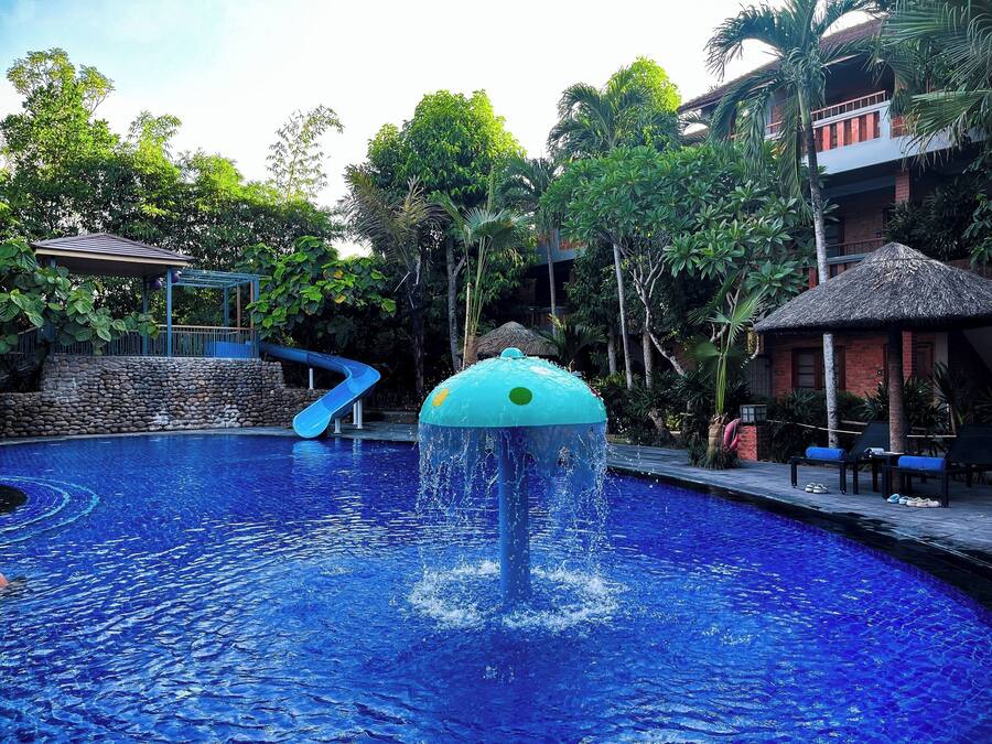 Una piscina con tobogán de agua y una estructura de techo de paja.