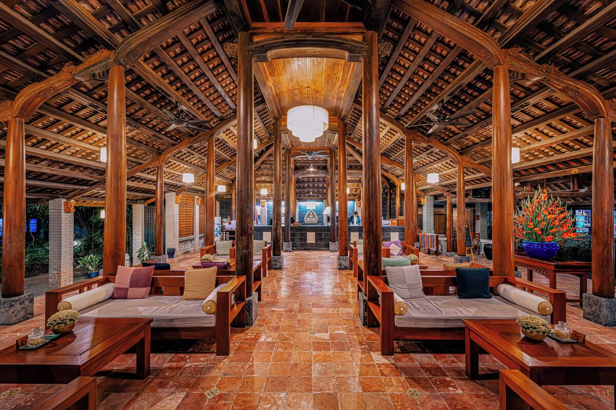 A spacious lobby with wooden furniture, a tiled floor, and a high wooden ceiling.