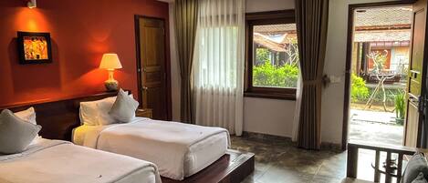 A hotel room with two beds, a sitting area, a ceiling fan, and a view of the outdoors.