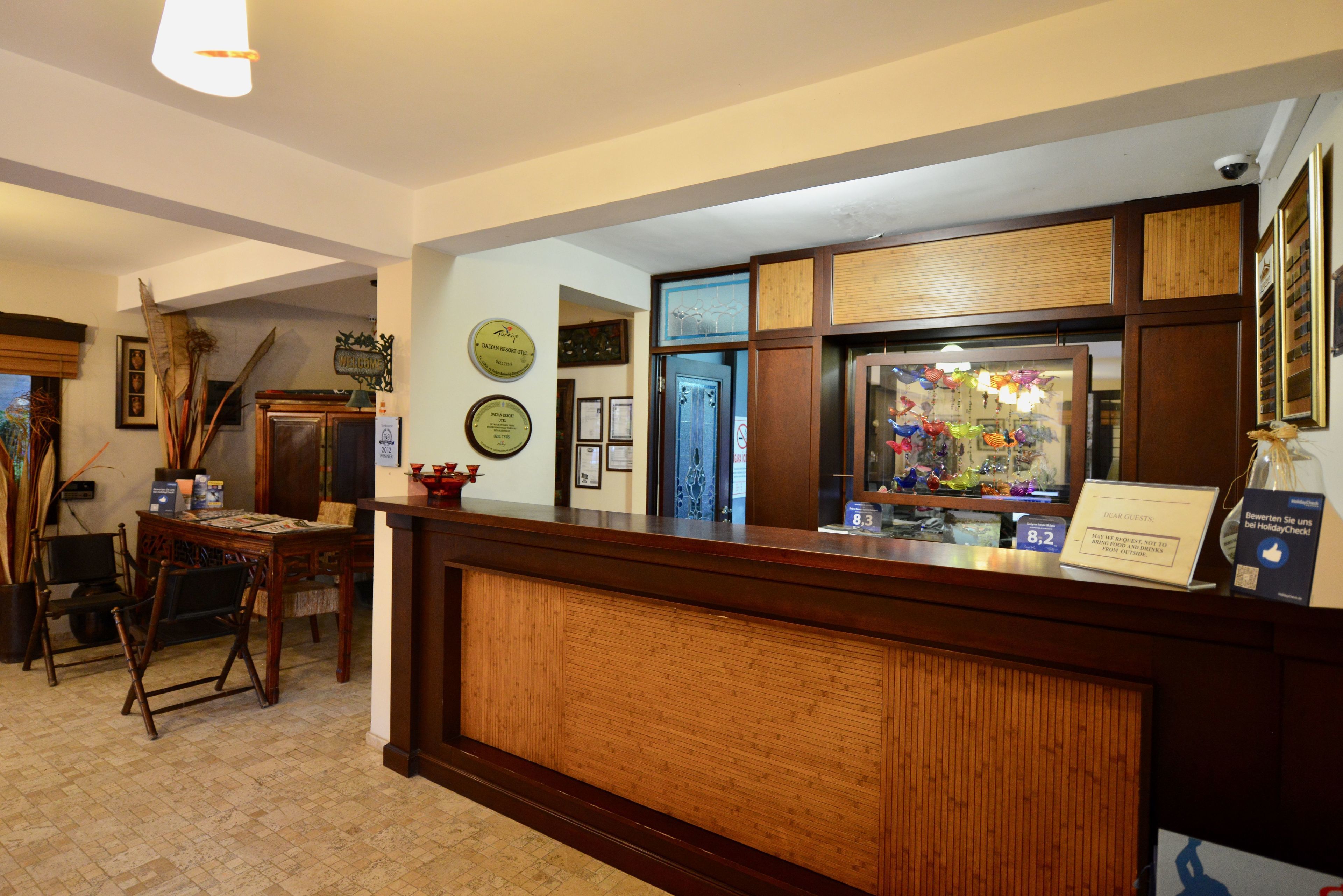 A reception area with a wooden reception desk, framed certificates on the wall, and a small seating area with chairs.