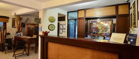 A reception area with a wooden reception desk, framed certificates on the wall, and a small seating area with chairs.