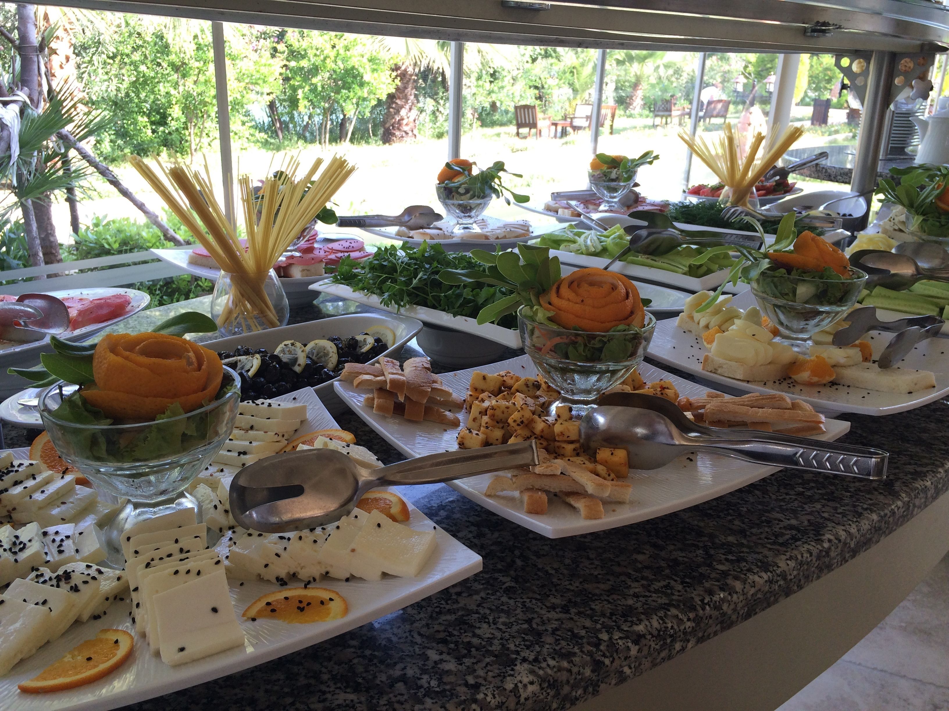 A buffet table with various food items including pasta, bread, and cheese.