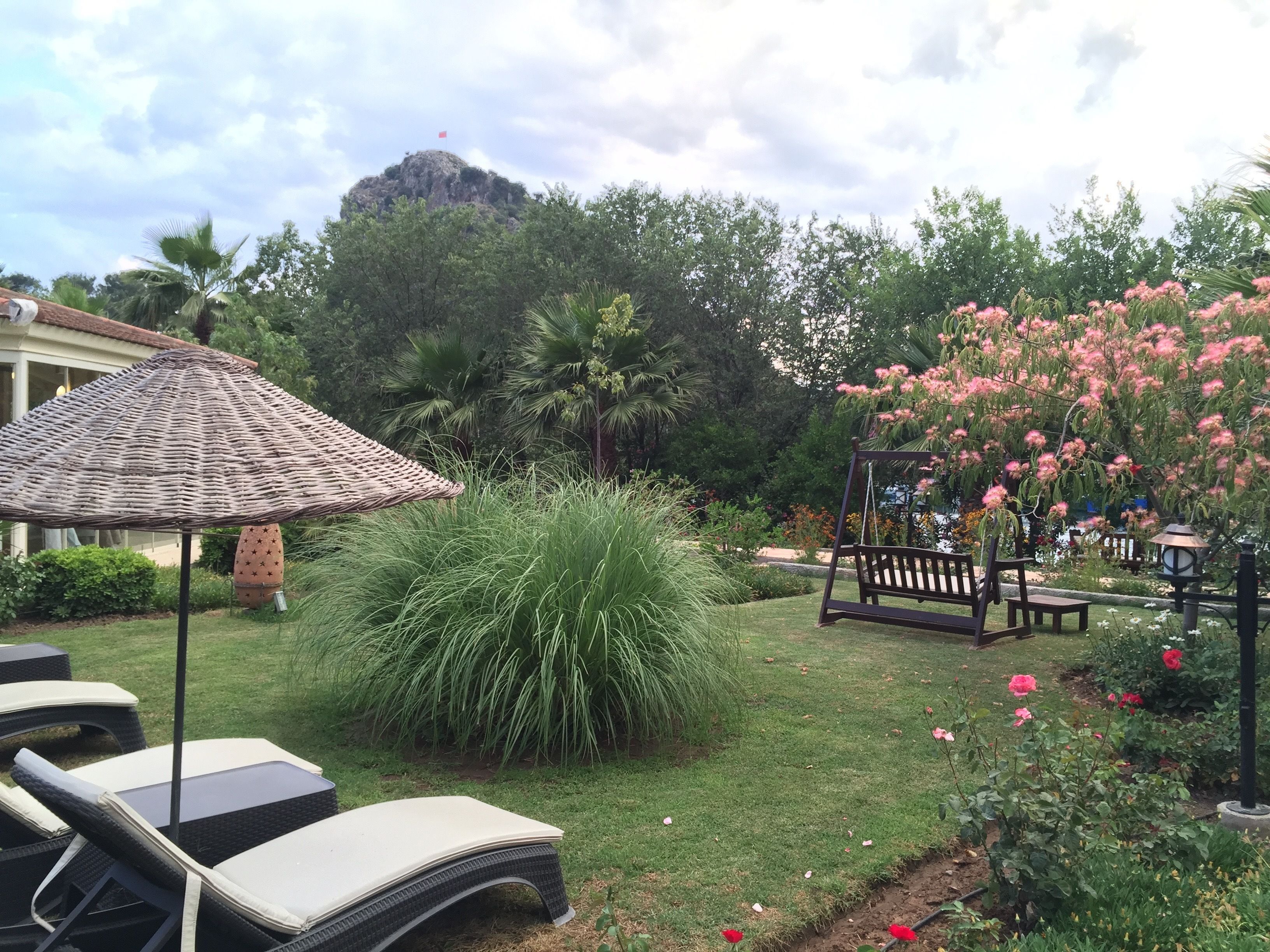 Um jardim com pérgola, balanço e área de estar com espreguiçadeiras.