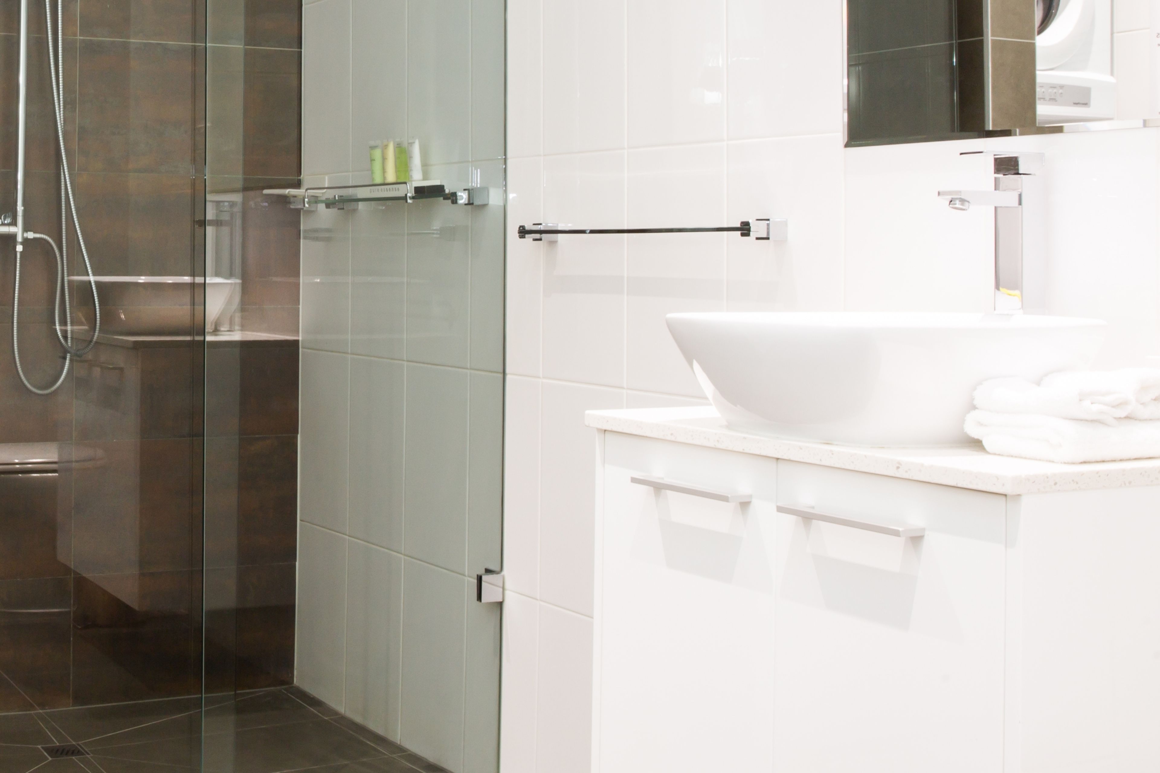 A modern bathroom with a glass shower enclosure, a white sink, and a mirror above it.