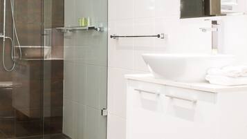 A modern bathroom with a glass shower enclosure, a white sink, and a mirror above it.
