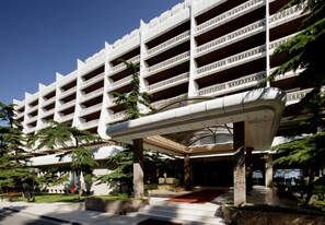Ein mehrstöckiges Hotel mit modernem architektonischen Design, mit Balkonen und einem überdachten Eingangsbereich.