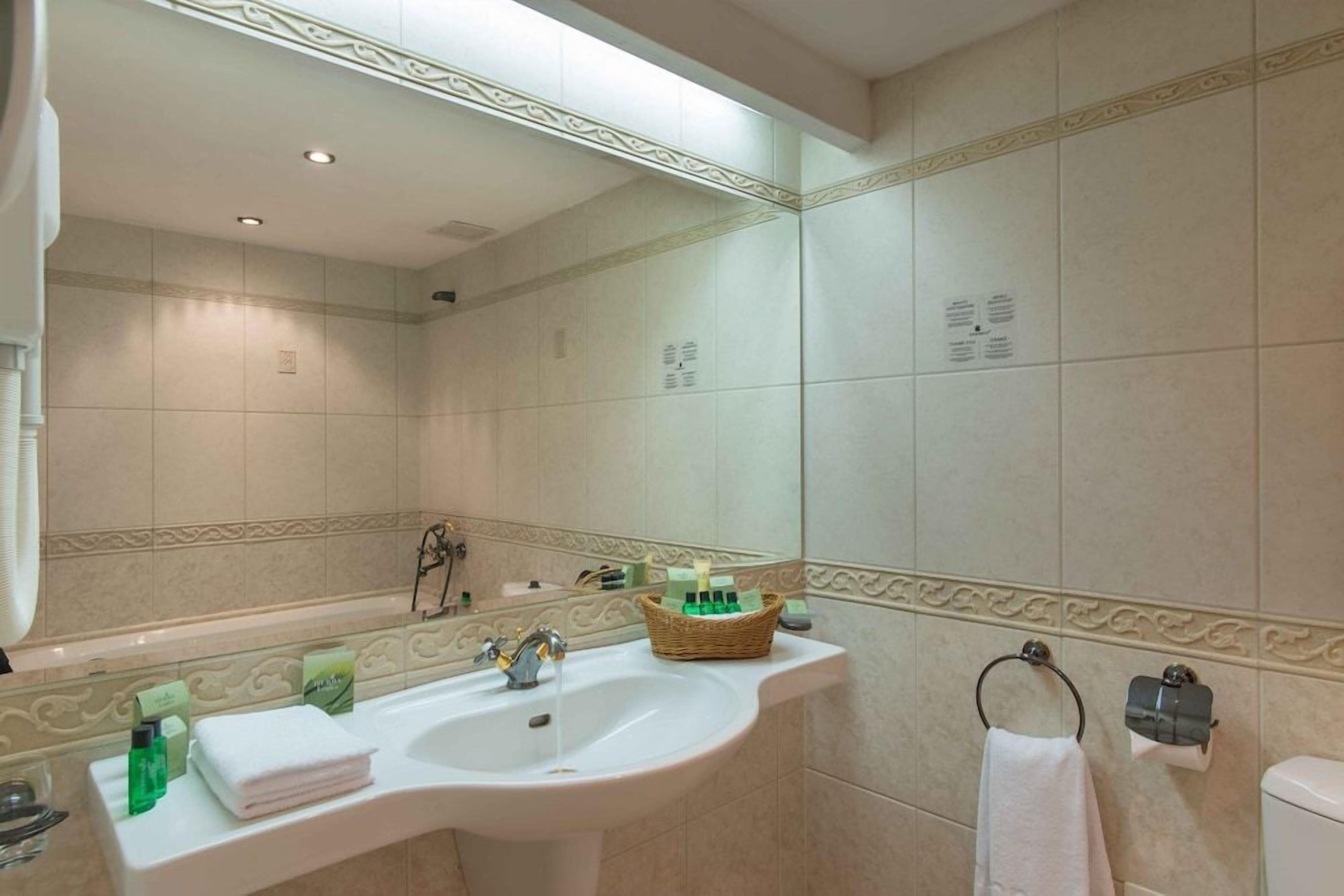 Un baño con lavabo blanco, un espejo y un perchero para toallas.