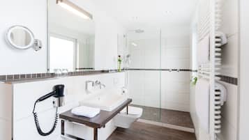 Un baño moderno con lavamanos, espejo y ducha.