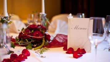 Una mesa adornada con una carta de menú, rosas rojas y pétalos de rosa dispersos.