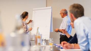 A meeting with a whiteboard, a bottle, and documents on a table.
