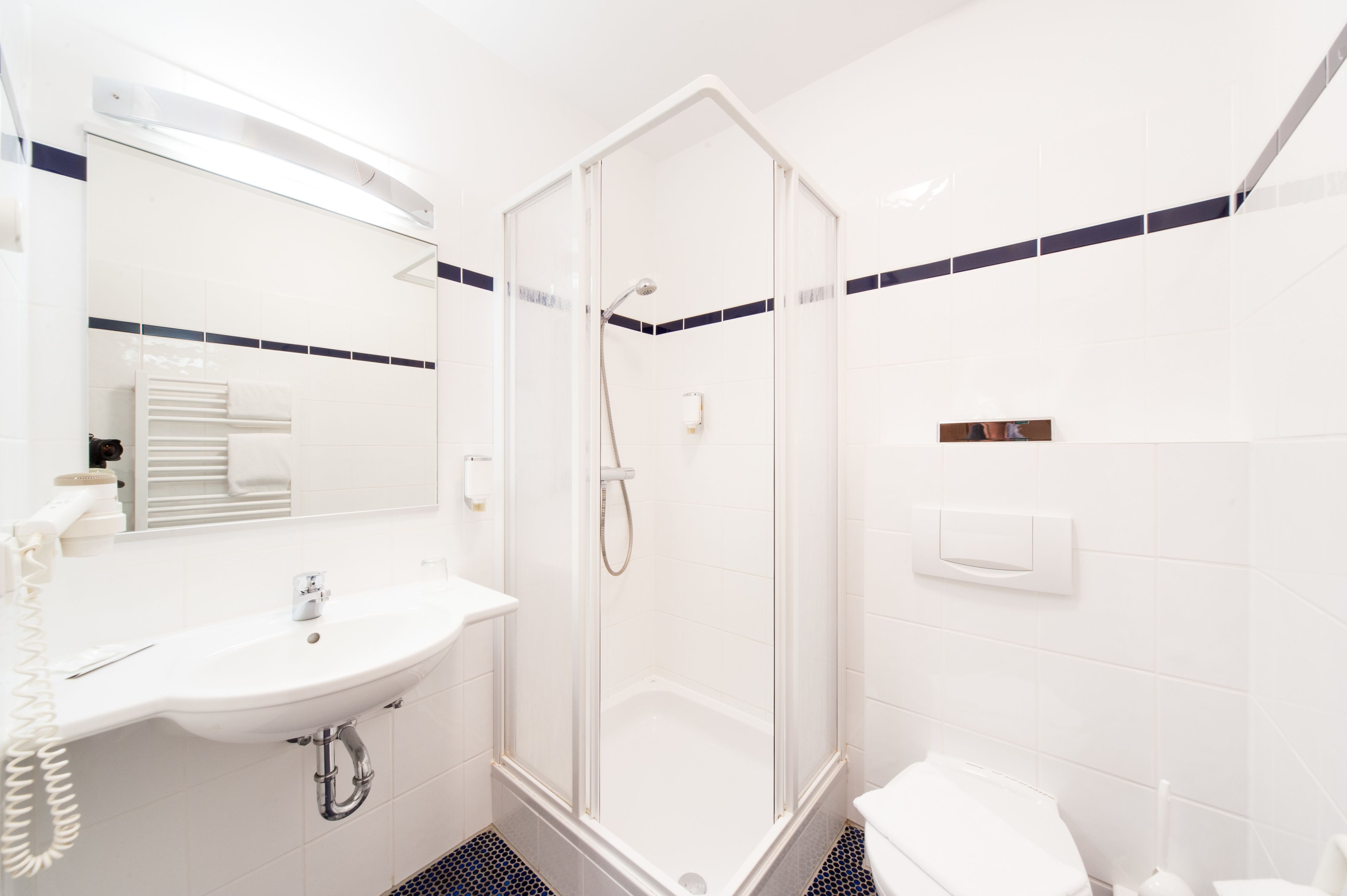 Une salle de bain moderne avec une douche à parois de verre, un lavabo blanc et des toilettes.