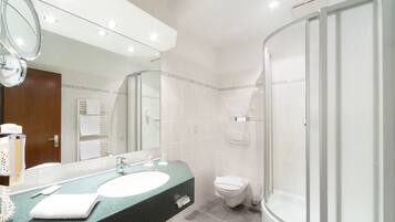 A modern bathroom with a large mirror, a sink, a toilet, and a shower.