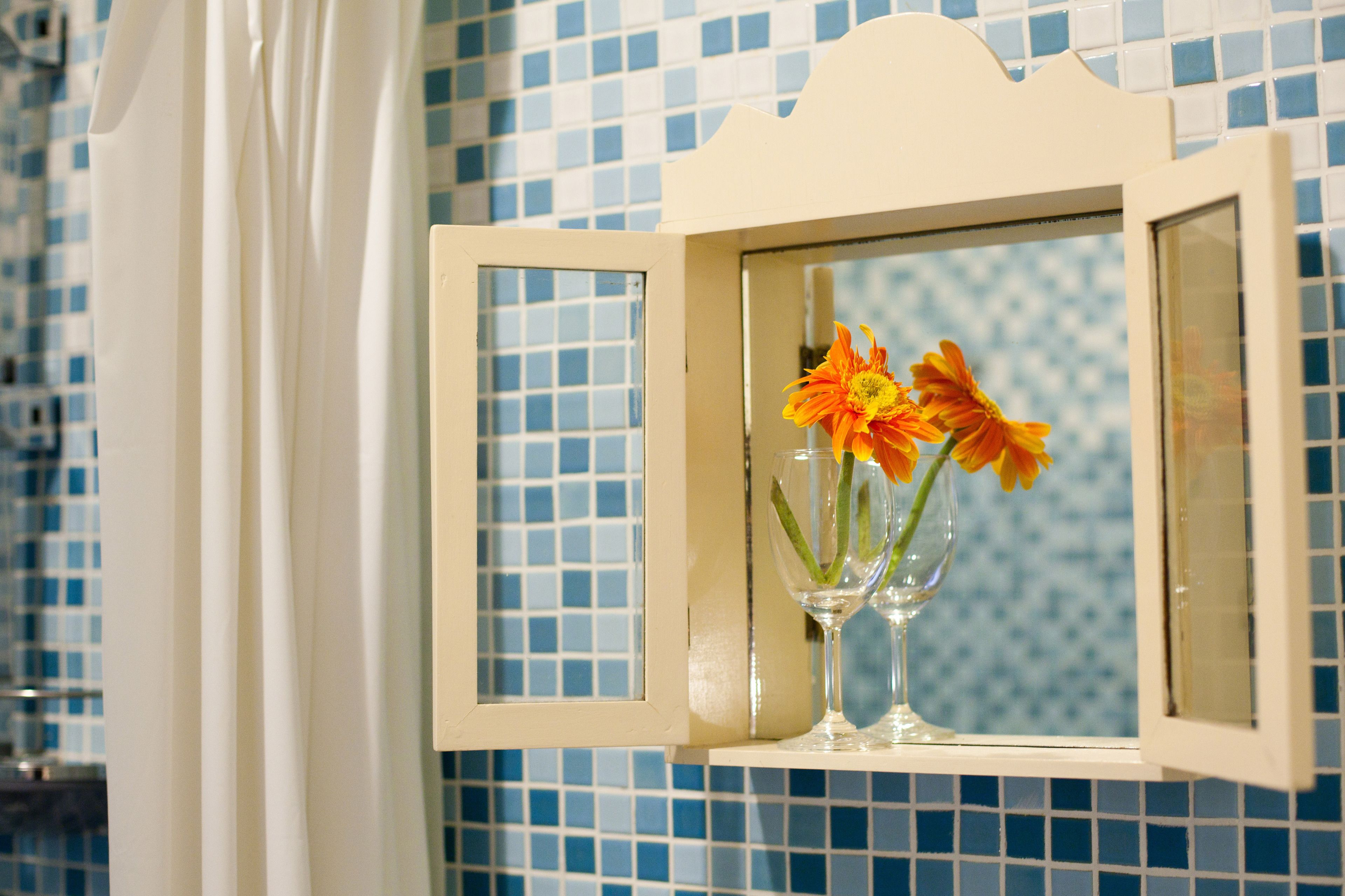 A bathroom with a tiled wall, a white shower curtain, and a window with a white frame.