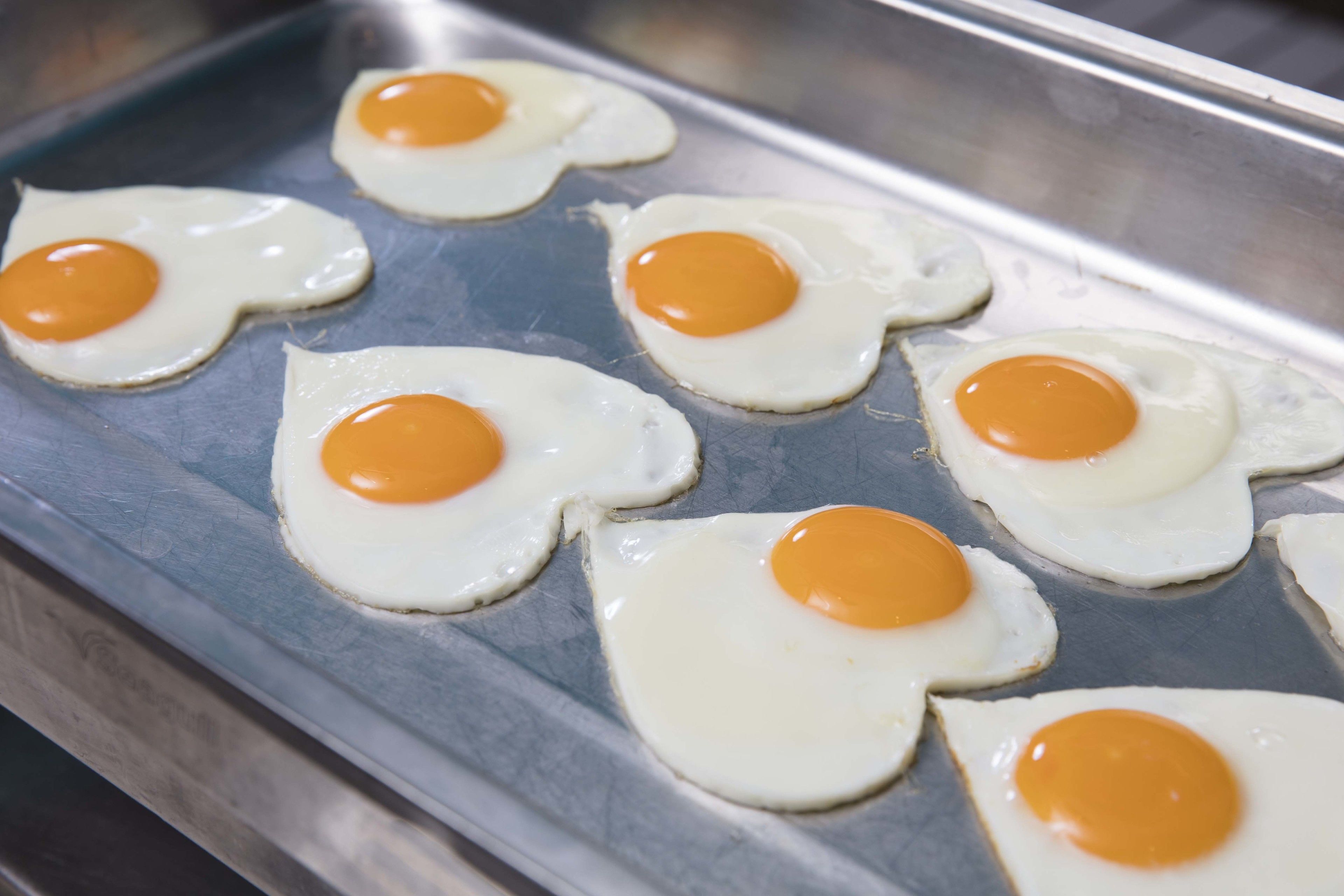 A tray of fried eggs with yolks intact.