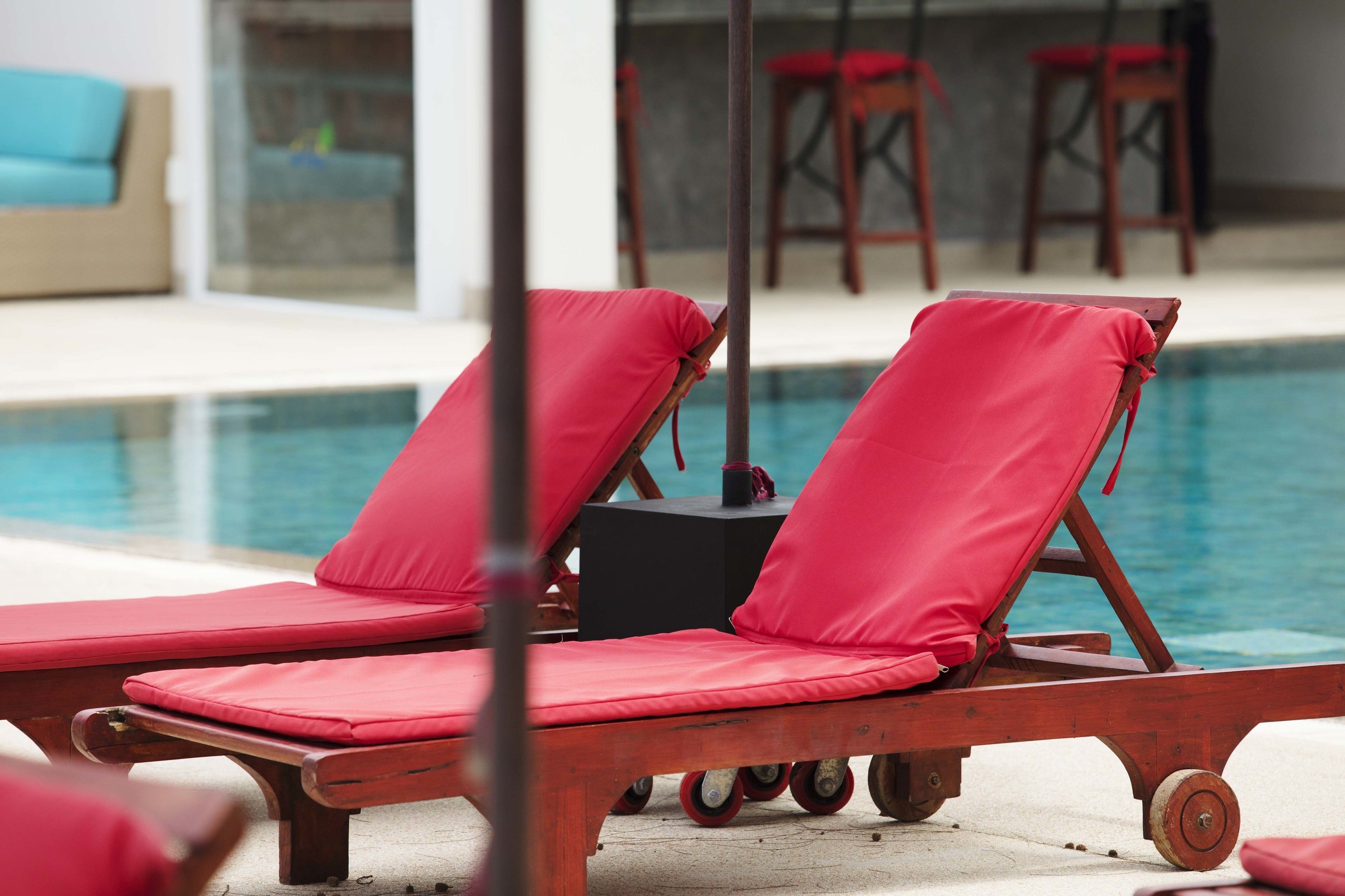 A poolside area with red lounge chairs and a table.