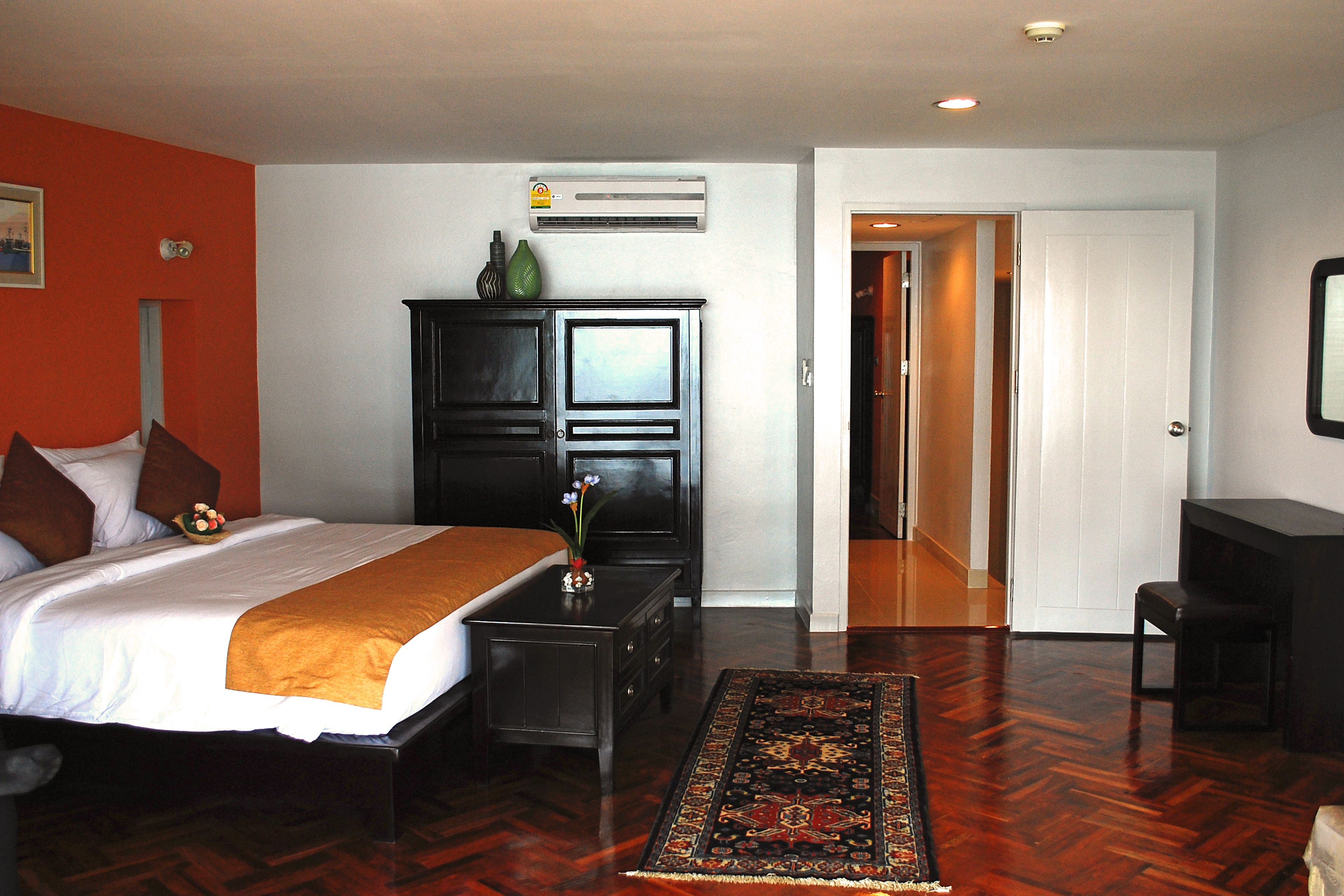 A hotel room with a bed, a nightstand, a dresser, a desk, and a chair.
