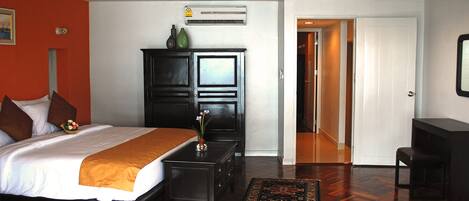 A hotel room with a bed, a nightstand, a dresser, a desk, and a chair.