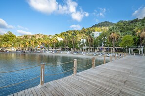 A wooden pier leading to a beach with lounge chairs and umbrellas. - Turunc Resort (Marmaris)