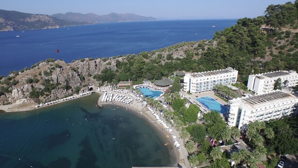 An aerial view of a coastal resort with multiple swimming pools, a beach, and a mountainous backdrop. - Turunc Resort (Marmaris)