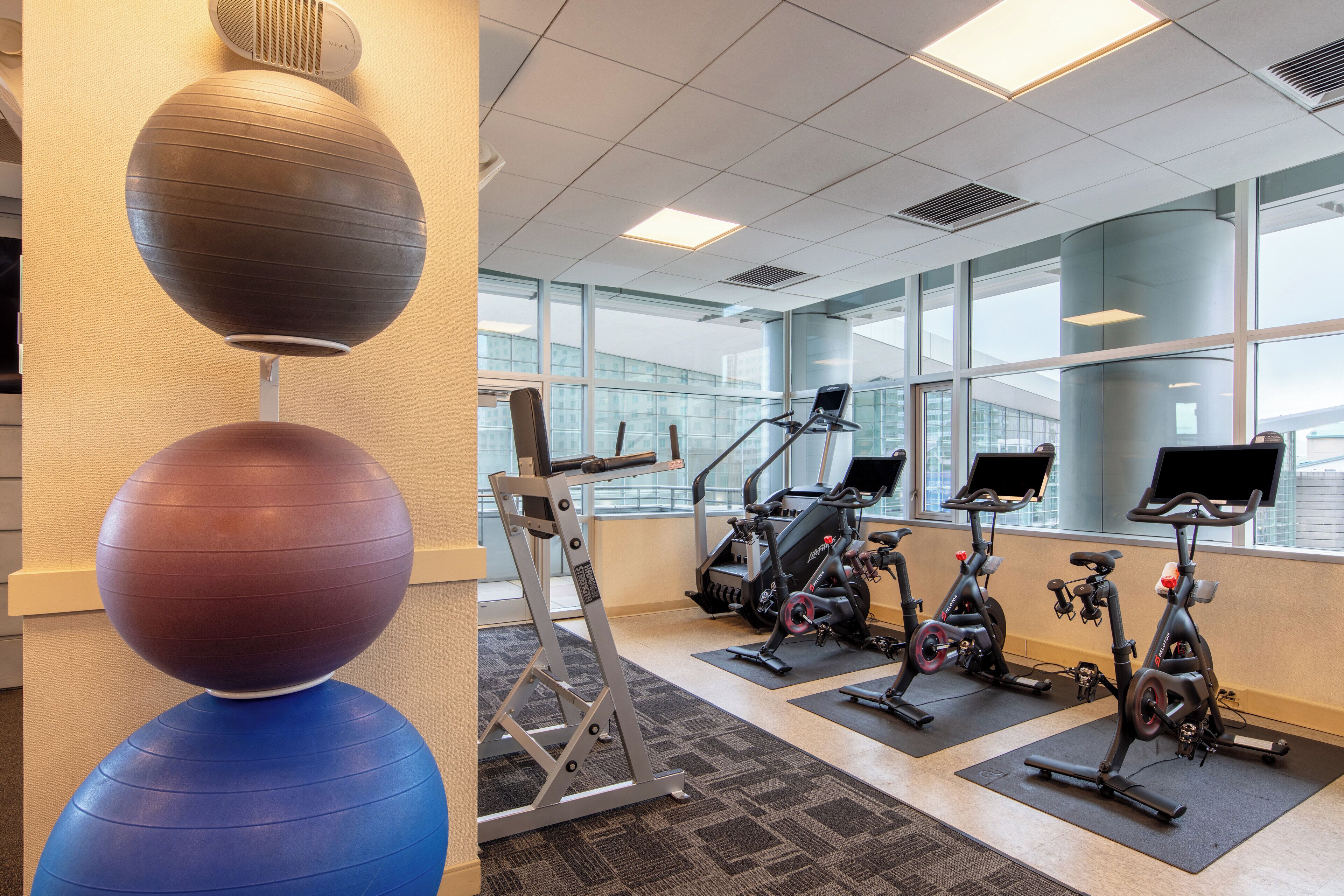 A gym with exercise equipment, including a treadmill, stationary bikes, and exercise balls.