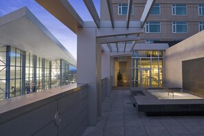 A modern building with large glass windows, a covered walkway, and a staircase leading to an entrance.