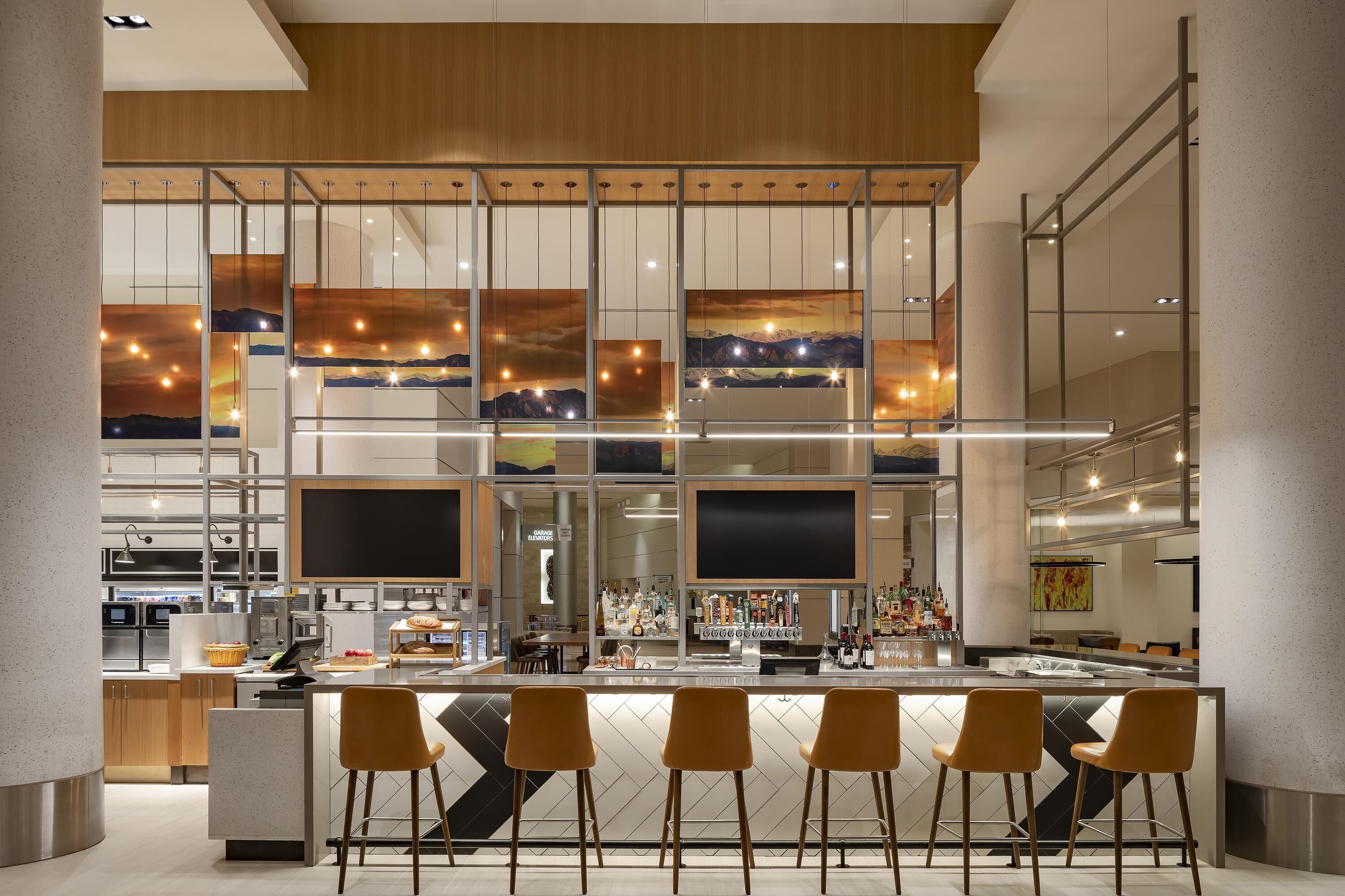 A modern bar area with a bar counter, seating, and a view of the kitchen area.