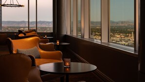 A modern lounge with leather seating and a view of a cityscape through large windows.