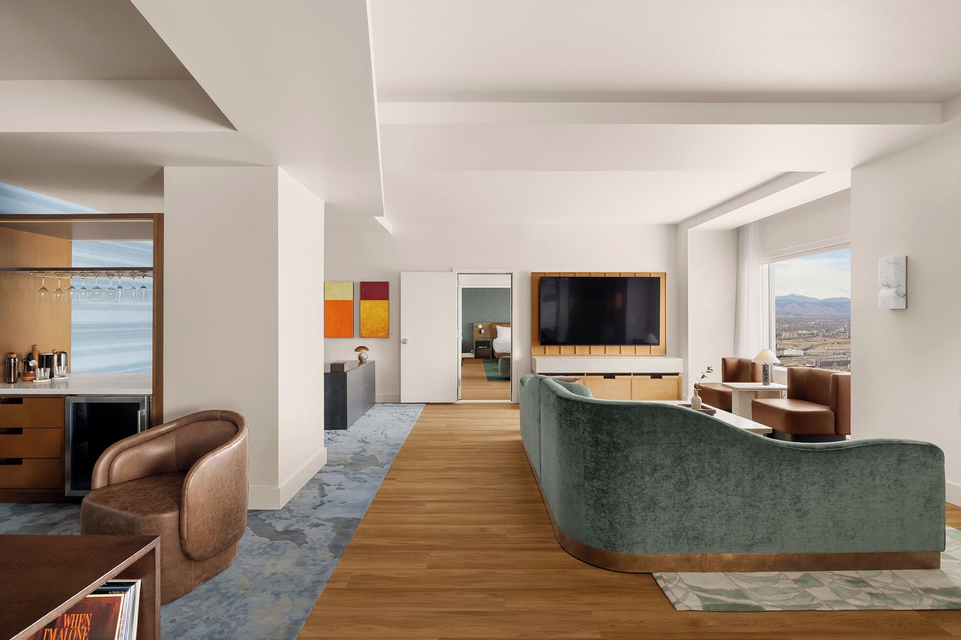 Een moderne woonkamer met een gebogen bank, een flatscreentelevisie en uitzicht op de stad.