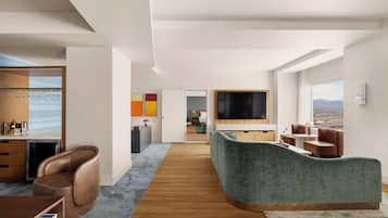 Een moderne woonkamer met een gebogen bank, een flatscreentelevisie en uitzicht op de stad.