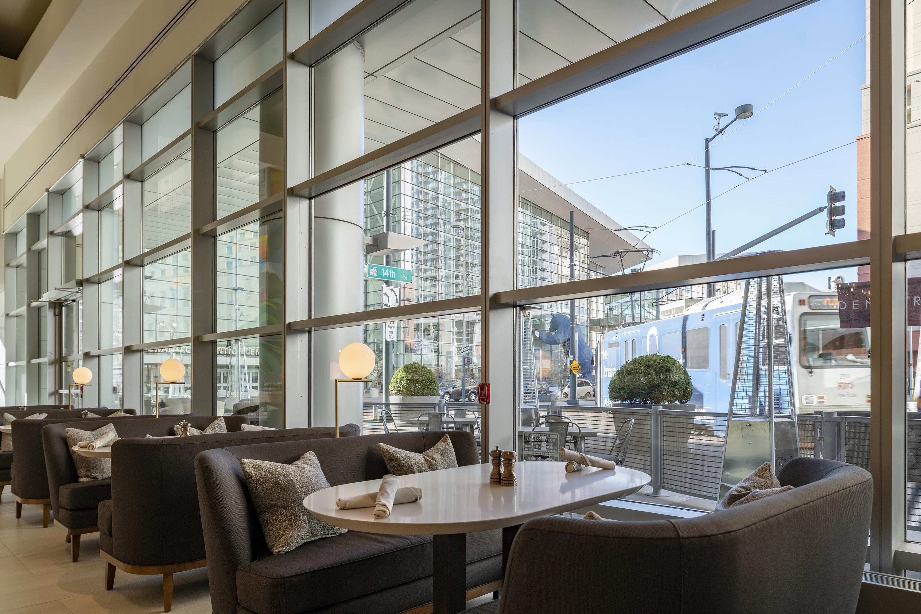 A modern interior with large windows, seating areas, and a view of the street.