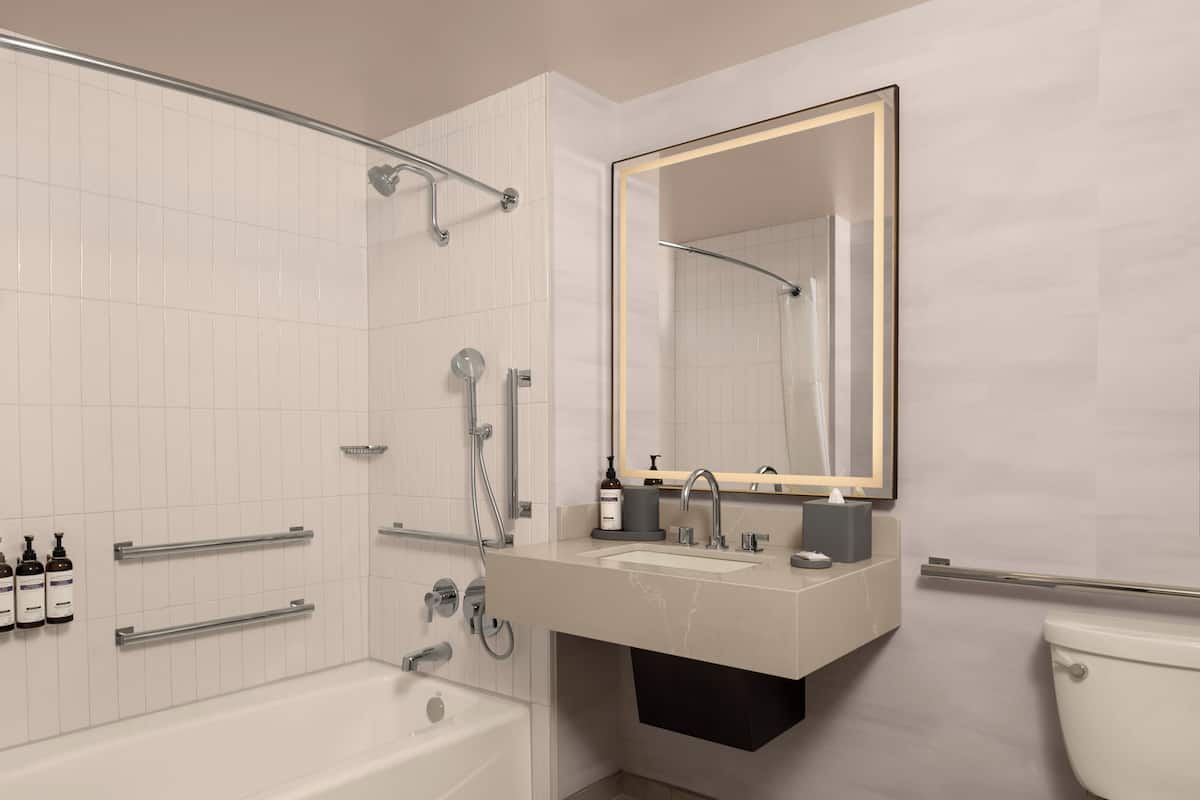 Un baño moderno con bañera, lavamanos con espejo e inodoro.