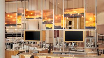 A modern bar area with a bar counter, multiple seating options, and a large window displaying a sunset view.
