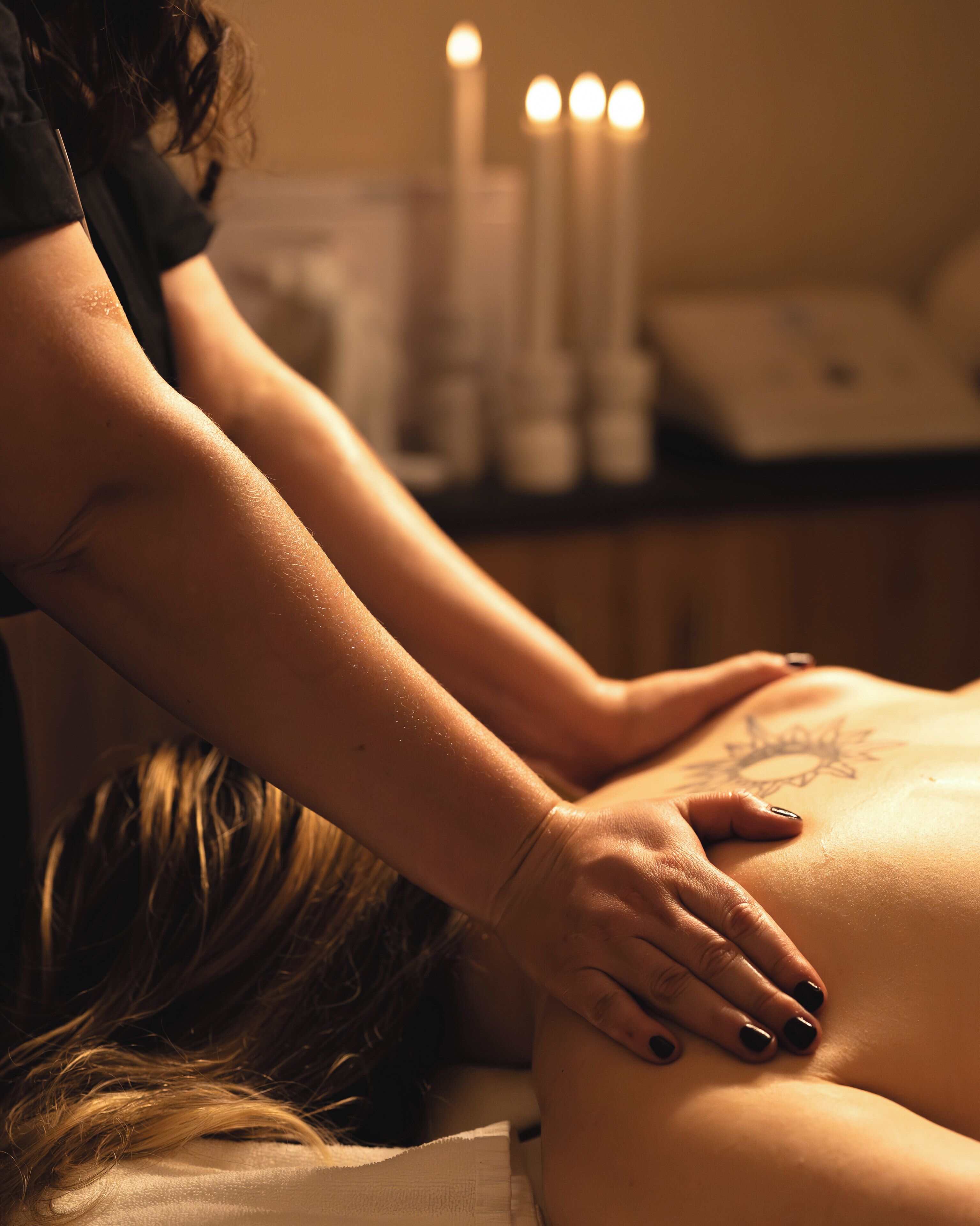 A massage therapy session in a dimly lit room with candles.